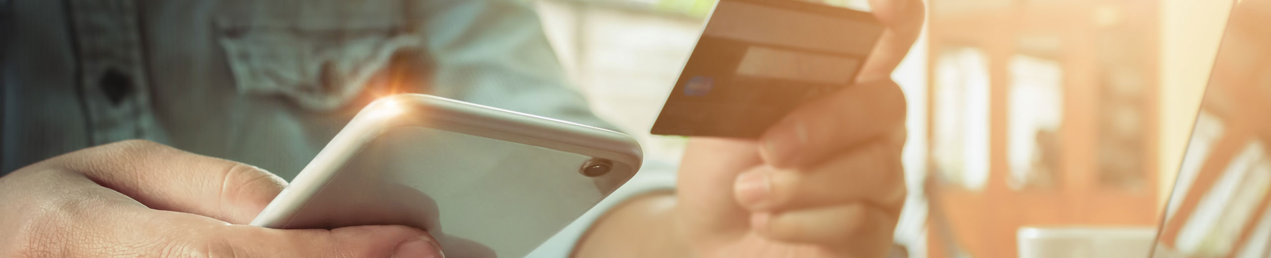 Man's hands holding smartphone and using credit card for online shopping.