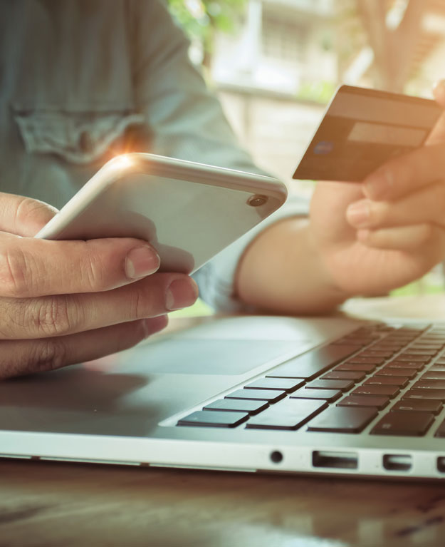 Man's hands holding smartphone and using credit card for online shopping.