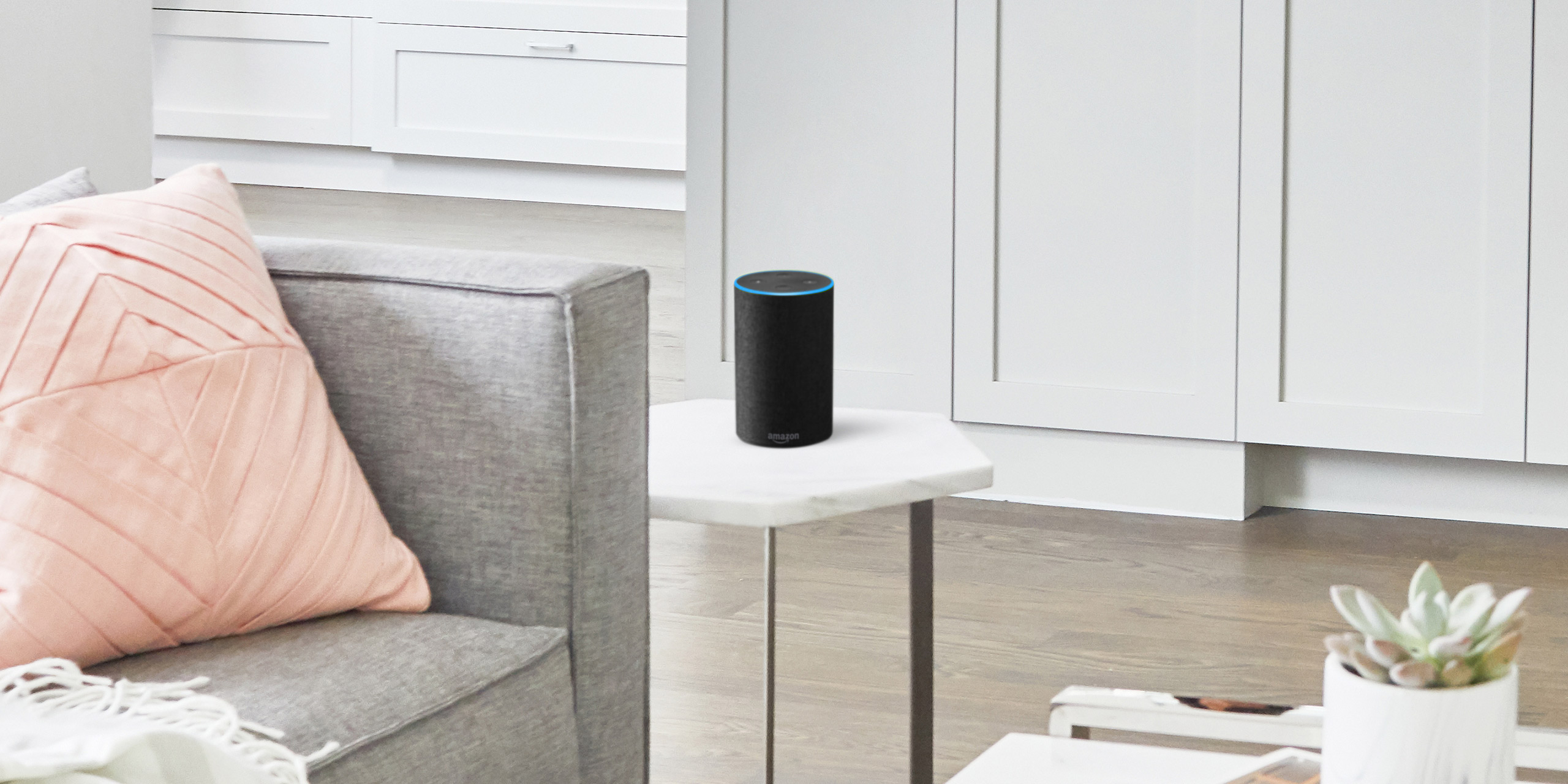 Wohnzimmer, in dem auf einem weißen Tisch Sprachassistentin Alexa steht
