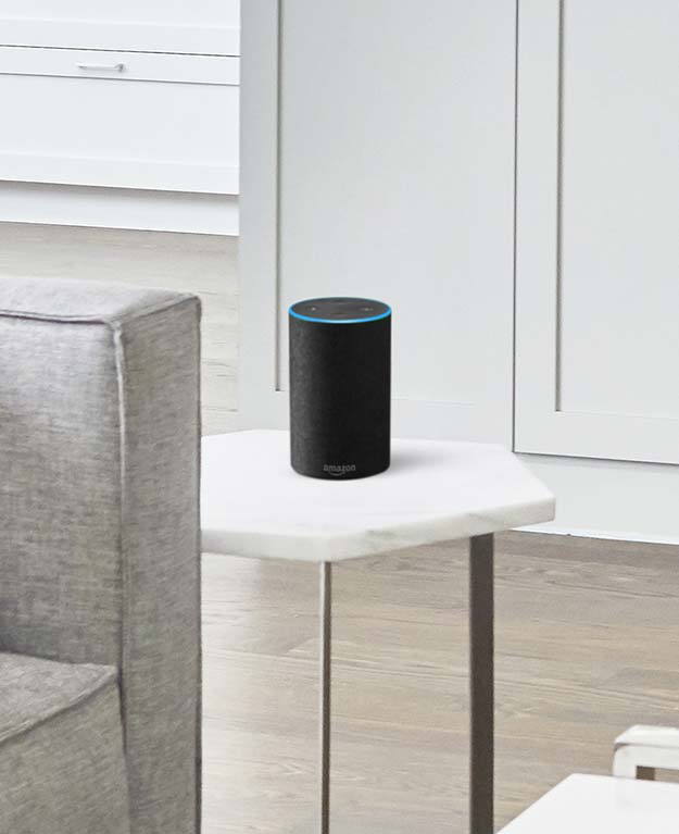 Wohnzimmer, in dem auf einem weißen Tisch Sprachassistentin Alexa steht