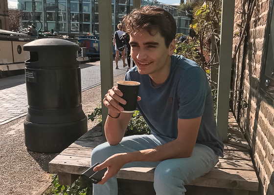 Wirtschaftsberater Maximilian trinkt einen Kaffee in der Sonne