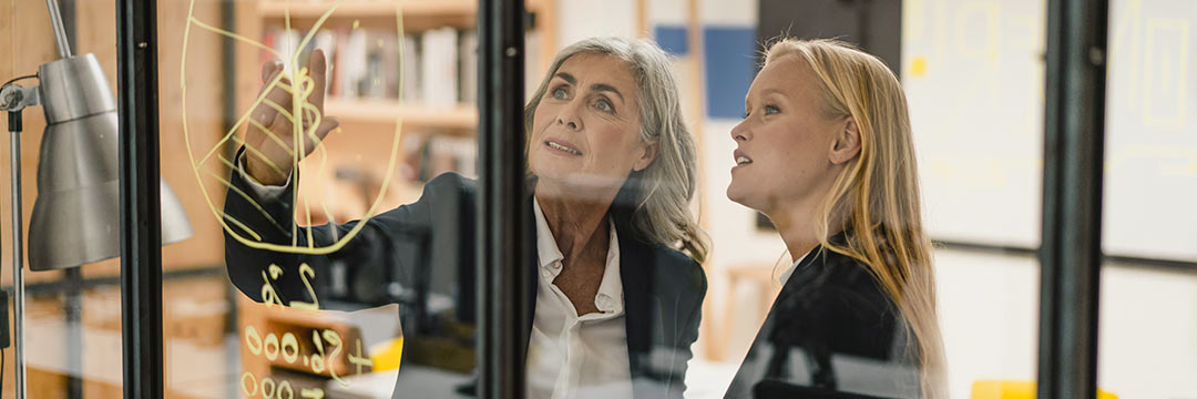 Zwei Frauen im Kostüm vor einem Glasboard