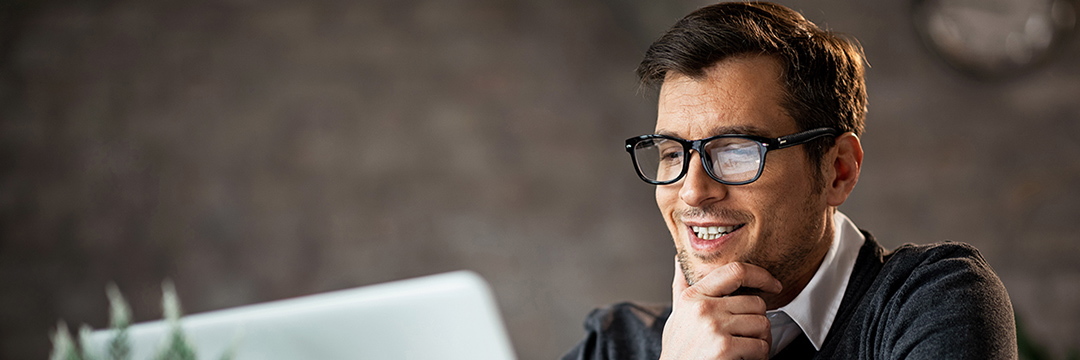 Mann sitzt vor dem Laptop