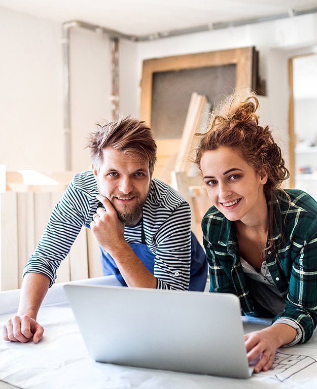A woman and a man stand in front of the laptop in a workshop