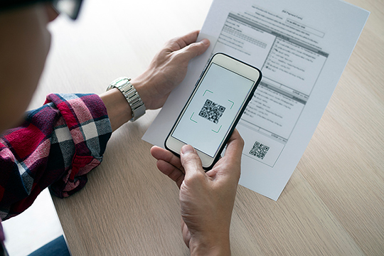 Ein Mann scannt einen QR-Code von einer Rechnung