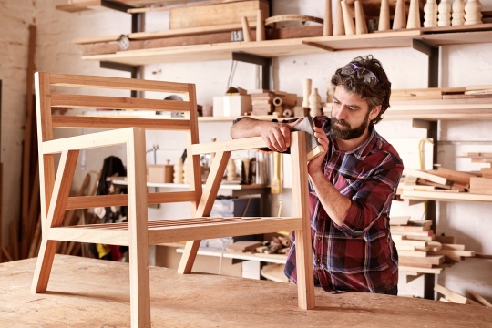 Ein Tischler arbeitet an einem Holzsessel