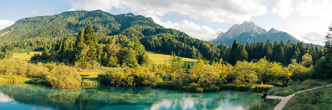 Ein See zwischen Wiesen und Wäldern