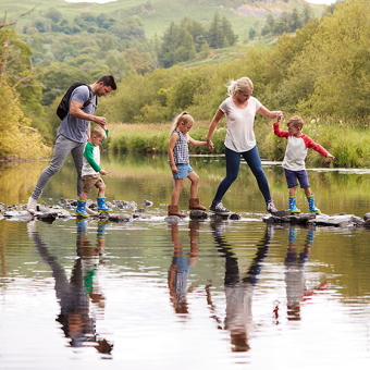Eine Familie geht über Steine in einem Fluss