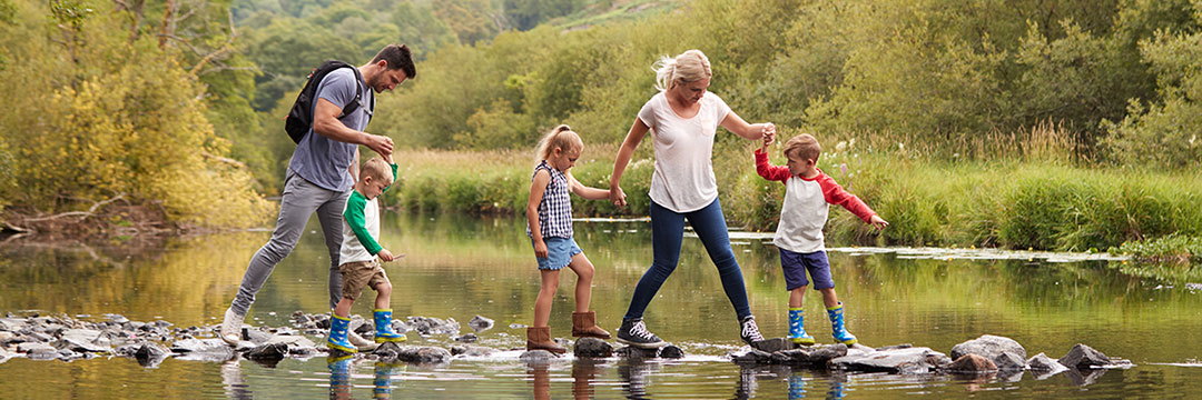 Eine Familie wandert über Steine durch einen Fluss