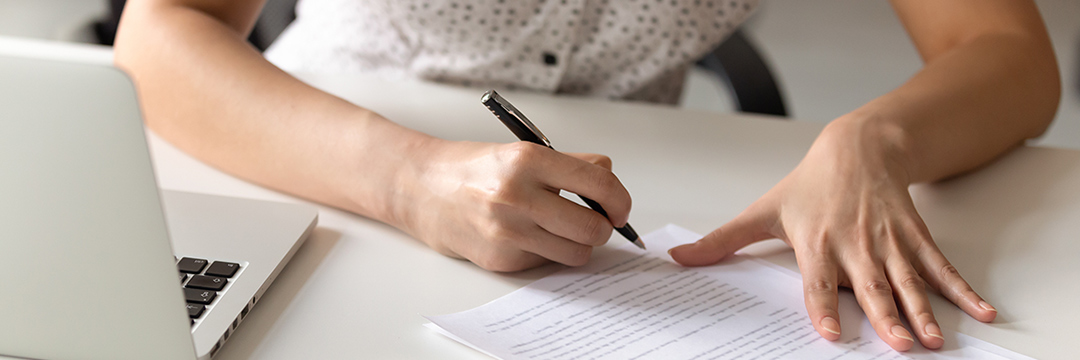 Eine Frauenhand schreibt etwas auf ein Blatt Papier
