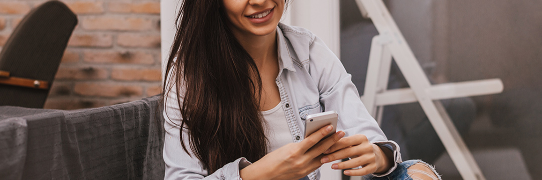 Eine junge Frau sitzt auf Stufen und schaut auf ihr Smartphone