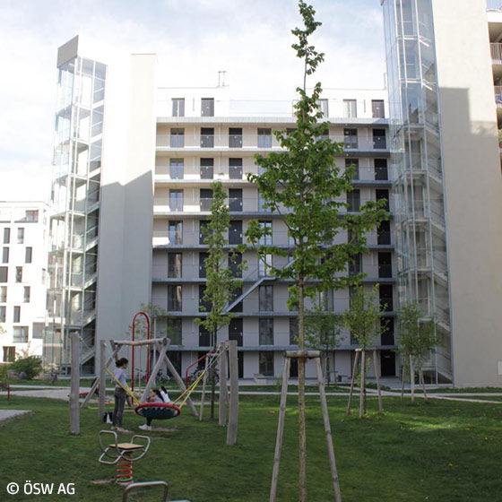 Im Hintergrund ein Hochhaus, im Vordergrund spielen zwei Kinder auf dem Spielplatz.